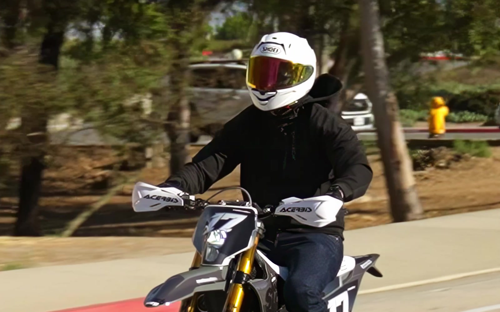 Cortech rider in black motorcycle gear riding through a sunlit street