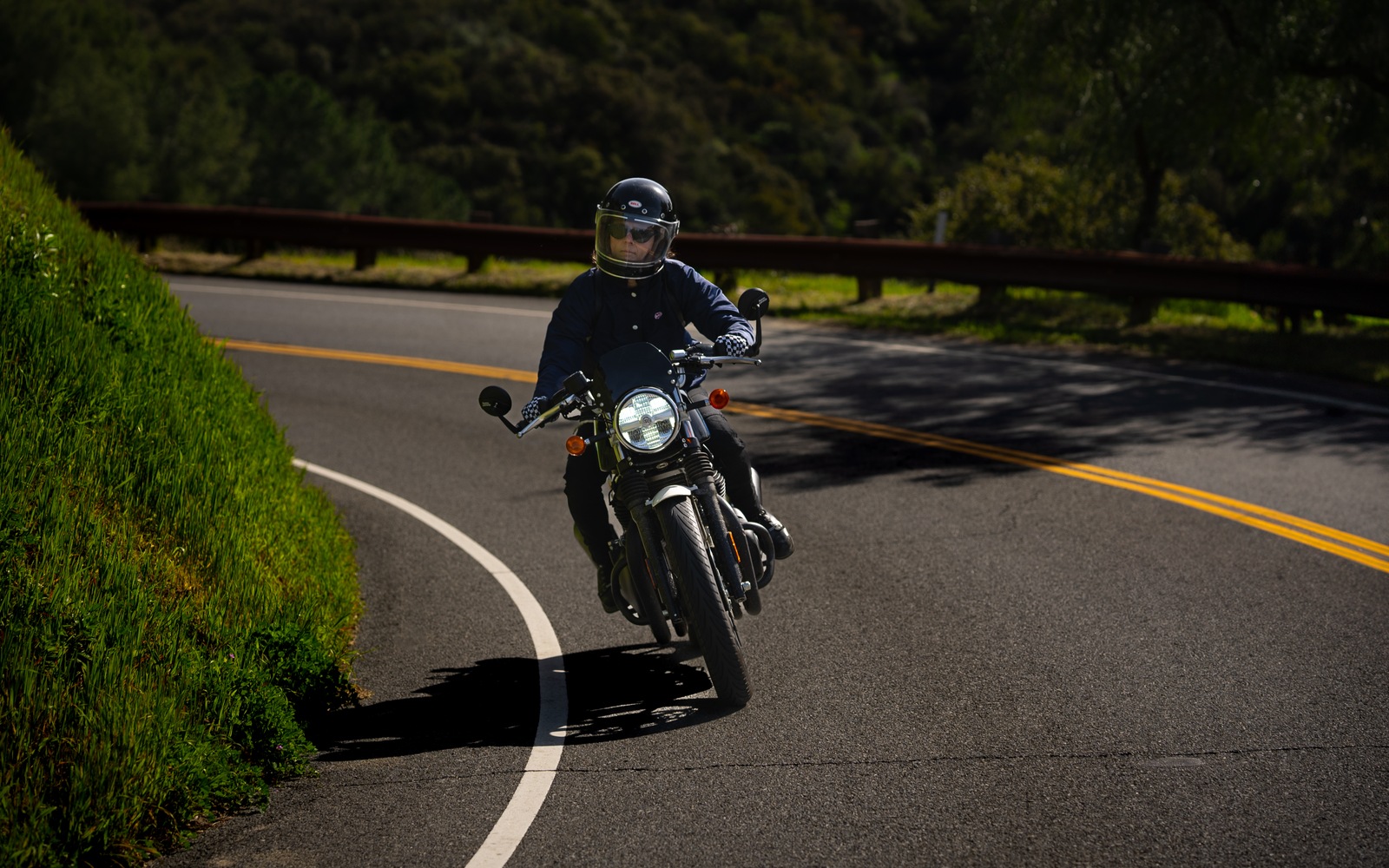 Royal Enfield rider leaning into a wooded road curve