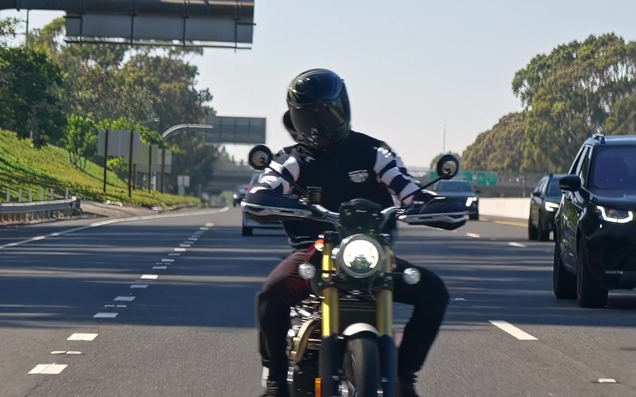 Triumph rider approaching on a sunlit road